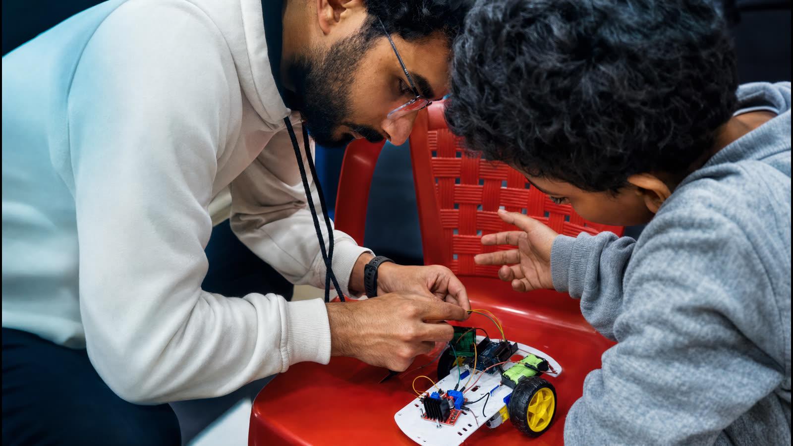 An instructor helping a student build a robot