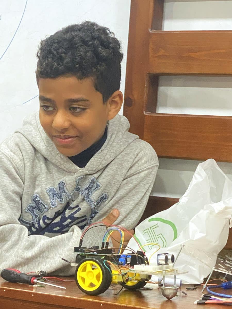 Mohamed standing happily in front of the robot he built